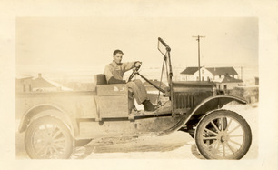 Person driving and old ford truck in a historical photo.