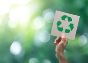 Hand holding up a sign with the recycle symbol