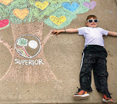 Child laying next to a three made of chalk with Superiors logo in the middle