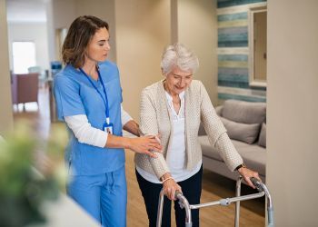 A nurse helps a senior with a walker