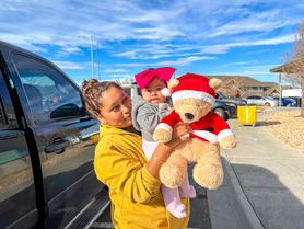 Mother and young child posing with a teddy bear.