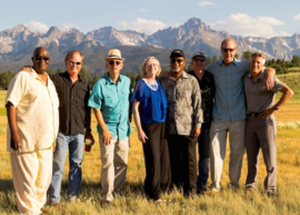 Eight band members of The Saints with Rocky Mountains in the background