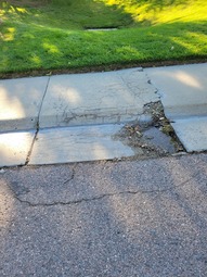 Damage concrete that makes up a portion of a sidewalk.