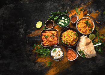 A spread of colorful Indian food on a gray table