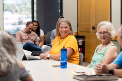 Person smiling while looking across a table during an Open Sace Advisory Committee meeting