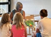 Cora Bracho of CBArt Studios holds an African mask craft on display for young artists.