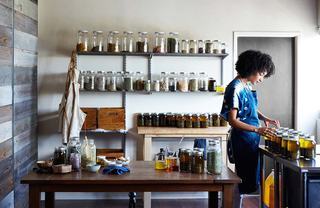 Woman working with artisan jars filled with colorful liquids.