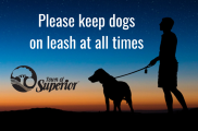 Silhouette of a person walking a dog with text "please leash your dogs"