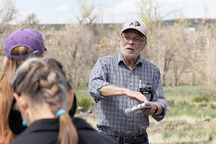 Historic Commission Chair Larry Dorsey talking during the 2023 Historic Walk with the trees of Old Town lining Coal Creek behind him.