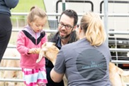 Child feeding a baby goat during National Trails Day 2023.