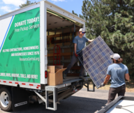 Two people loading waste from a renovation project into a box truck.