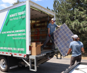 Two people loading waste from a renovation project into a box truck.