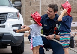 Children with firemen using a fire hose during National Night Out.