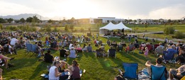 People enjoying the Summer Concert series with the sun setting over the moutains in the background.
