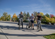 Three teens stop to talk while riding e-bikes.