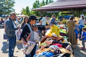 Person with a baby looks through a collection of costumes at the 2023 Ecotoberfest Costume Exchange.