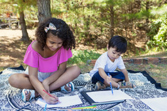 Children sitting on a blanket creating art