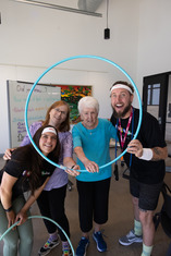Two seniors and two class instructors smiling through a hula hoop at Bingocize