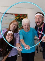 Two seniors and two class instructors smiling through a hula hoop at Bingocize