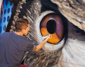 Artist AJ Davis spray paints a mural 