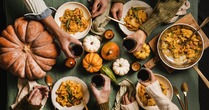 Fall themed meal with guests toasting and pumpkins as decor.
