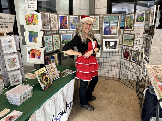 Woman surrounded by art at her Sister City: Holiday Bazaar booth