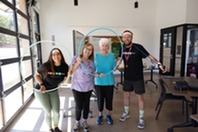 Two seniors and two class instructors smiling through a hula hoop at Bingocize