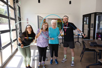 Two seniors and two class instructors smiling through a hula hoop at Bingocize