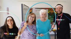 Two seniors and two class instructors smiling through a hula hoop at Bingocize