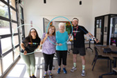 Two seniors and two class instructors smiling through a hula hoop at Bingocize