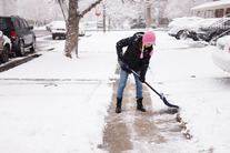 Person shovels snow from the sidewalk