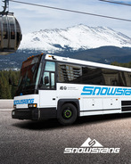 Snowstang bus in front of a gondola and mountain view.