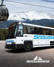 Snowstang bus in front of a gondola and mountain view.