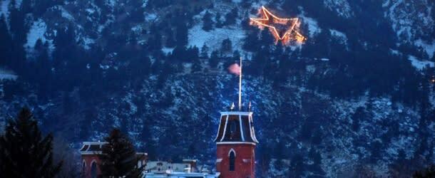 Flagstaff star glowing behind and building on the mountain side.