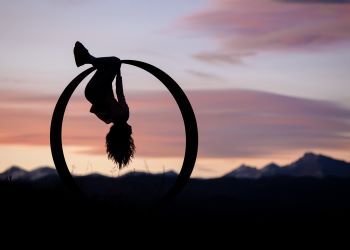 Image of a girl hanging on a ring in front of a sunset from In My Orbit from Andrew Vaughan