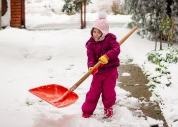 A young girl bundled up shovels snow