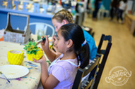 A kid paints a ceramic pineapple in a Createry workshop