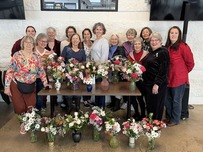 Group of seniors smiles with flower arrangements at the Superior Community Center