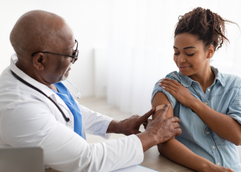 A doctor puts a bandage on a patient's arm