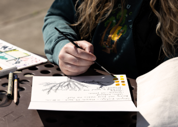 A person paints with watercolors during a Nature Journaling class in Superior