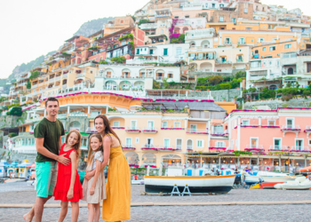 Four family members pose for a photo in front of an Italian landscape
