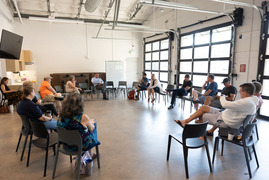 a group sits in a circle of chairs at the SCC conversing with council members for the first fridays event