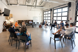 a group sits in a circle of chairs at the SCC conversing with council members for the first fridays event