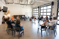 a group sits in a circle of chairs at the SCC conversing with council members for the first fridays event