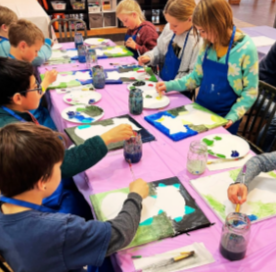 kids painting on canvases on a pink table