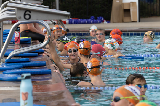 a bunch of swimmers on the flyers team gather in the pool prior to the swim meet