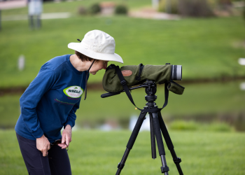 A woman looks through a spotting scope at Purple Park