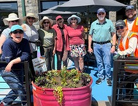 group of seniors gather around a large pink planter box outside the SCC for the Dig In! Gardening Workshop