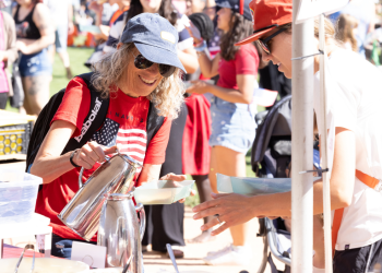 A woman pours syrup on pancakes at the 4th of July Pancake Festival