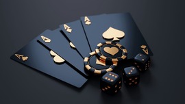 black playing cards, poker chips, and dice with gold letting sit against a black background